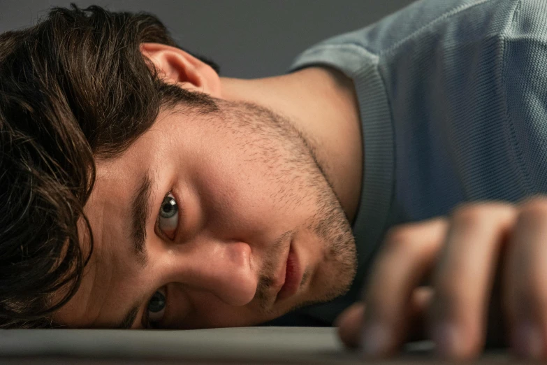 a young man looks over his shoulder in a dark room