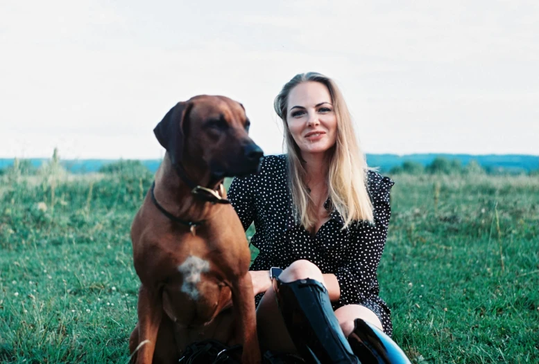 a woman sitting on the ground with her dog