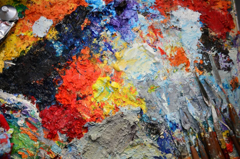 a palette with several different colors of paint and two black brushes