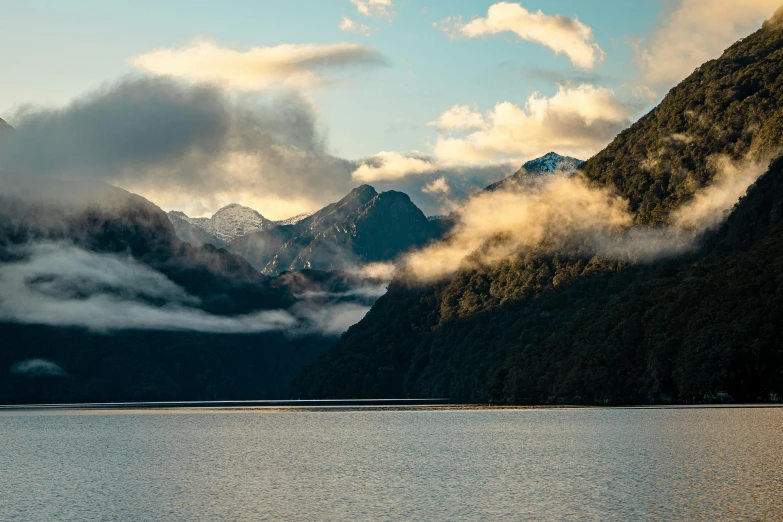 clouds float over mountains on a lake