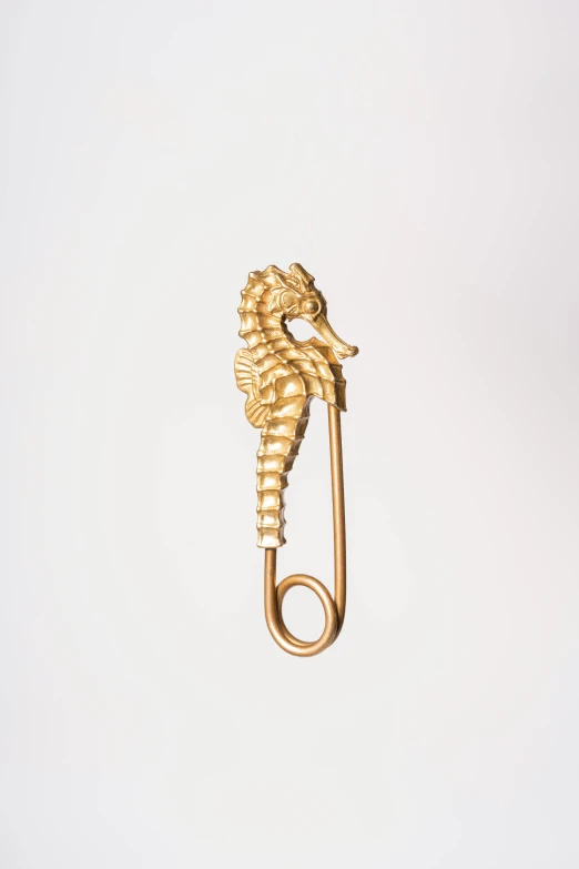 a golden metal hook with a sea horse on top