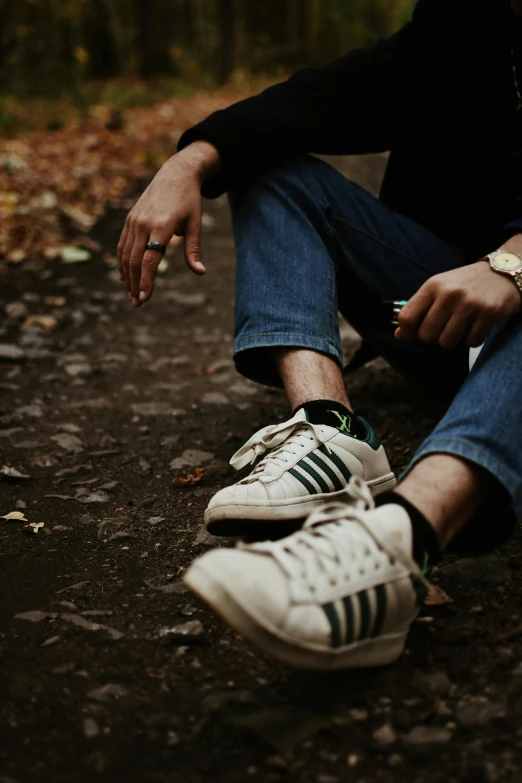 person tying white tennis shoes sitting on ground