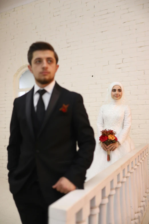 a bride and groom stand near a railing holding flowers