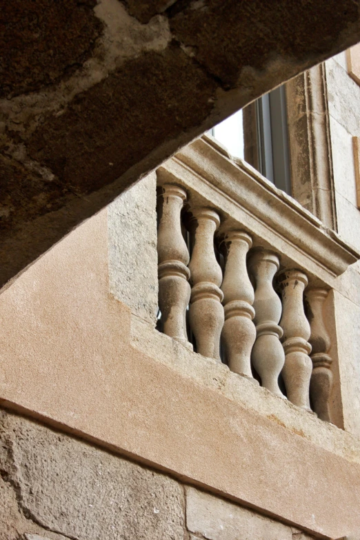 a stone window on a wall near an iron rail