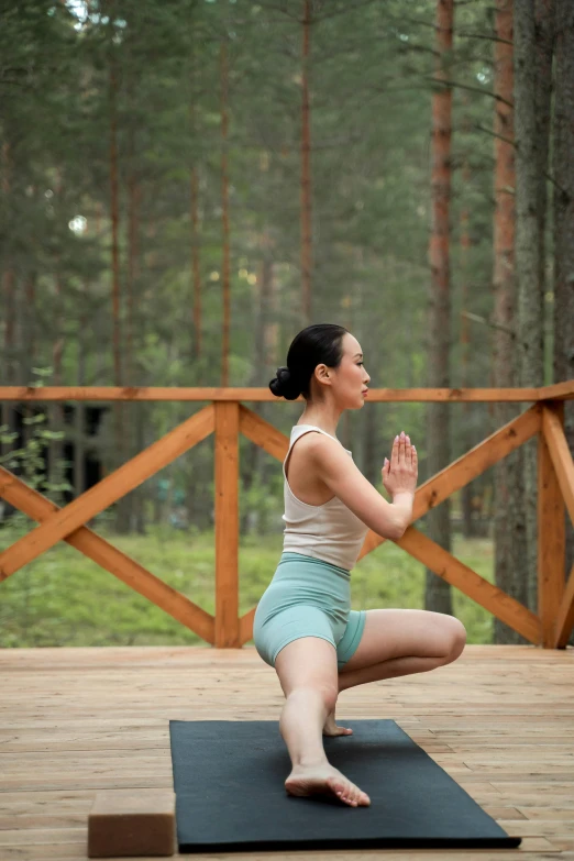 a woman is practicing yoga on a mat on the porch