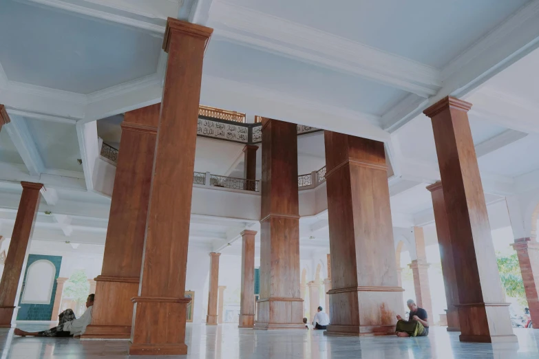 a few people sit under some wooden pillars