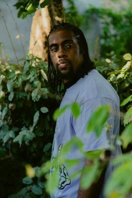 a man in a green shirt standing next to plants