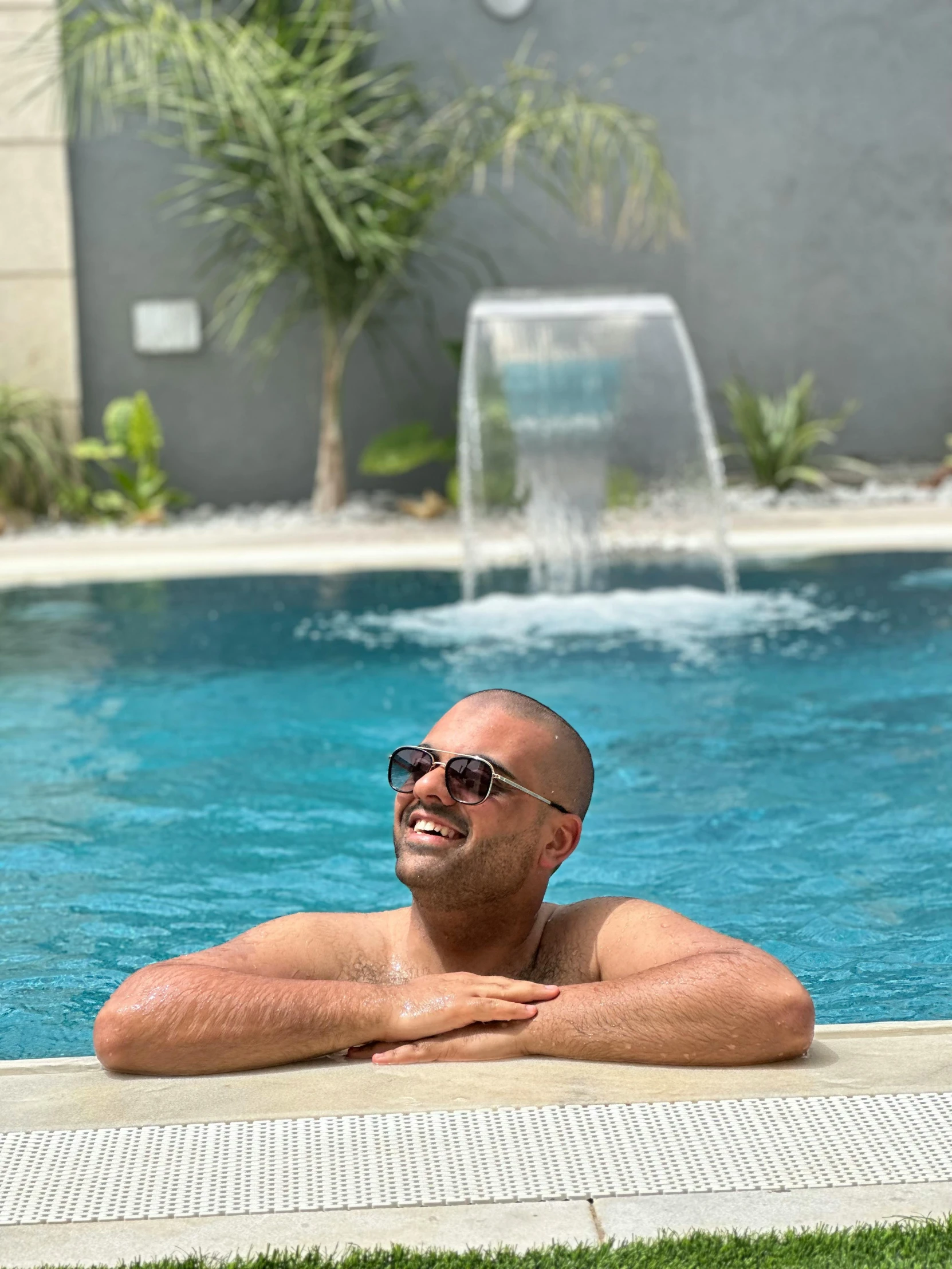 the man is smiling next to the pool