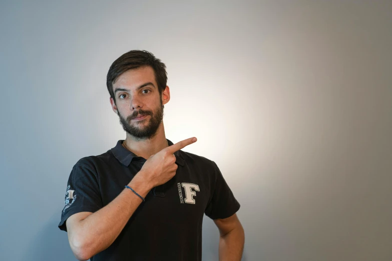 a man in a polo - shirt pointing with his finger