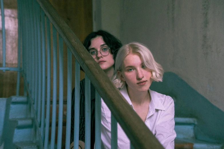 two women are leaning up against the railing