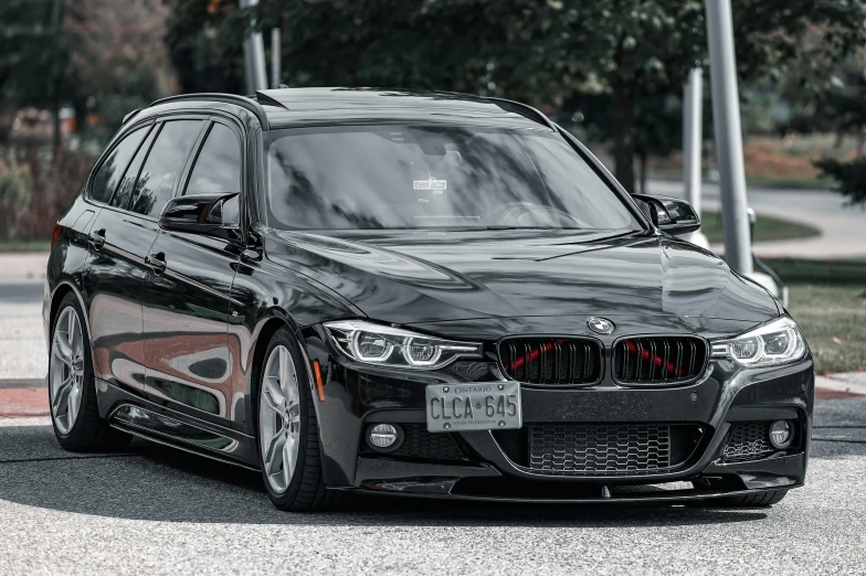 the black bmw car parked in front of some trees