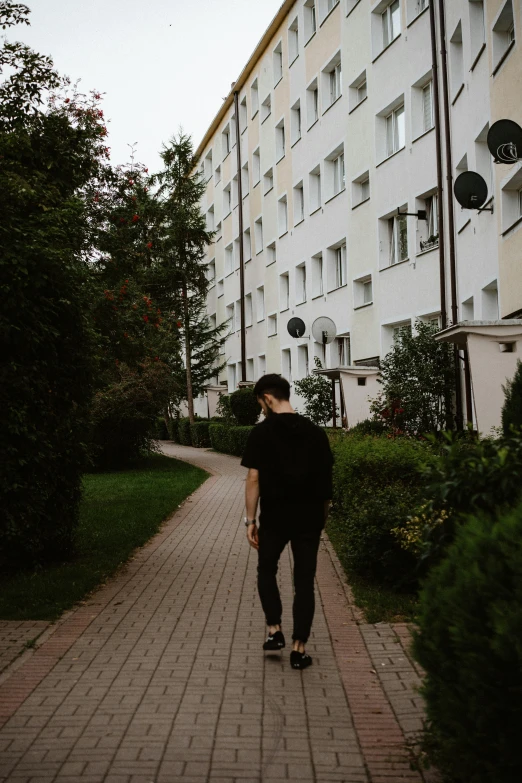 a man in black walking along a brick road