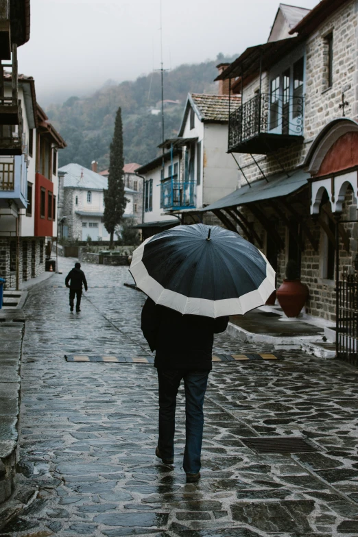 a person walking down a stone street with a umbrella