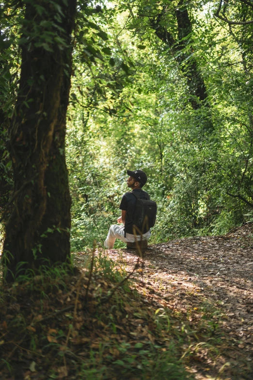 a boy is sitting on a bench in a forest