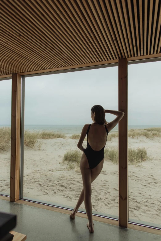 a woman in a black one piece stands by an open door