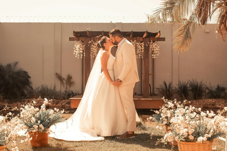 bride and groom sharing a kiss underneath a pergolia arch