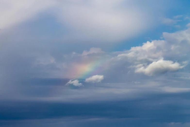 a rainbow is in the sky with clouds above