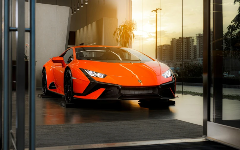 orange, sporty car sitting in a showroom with sun shining through it