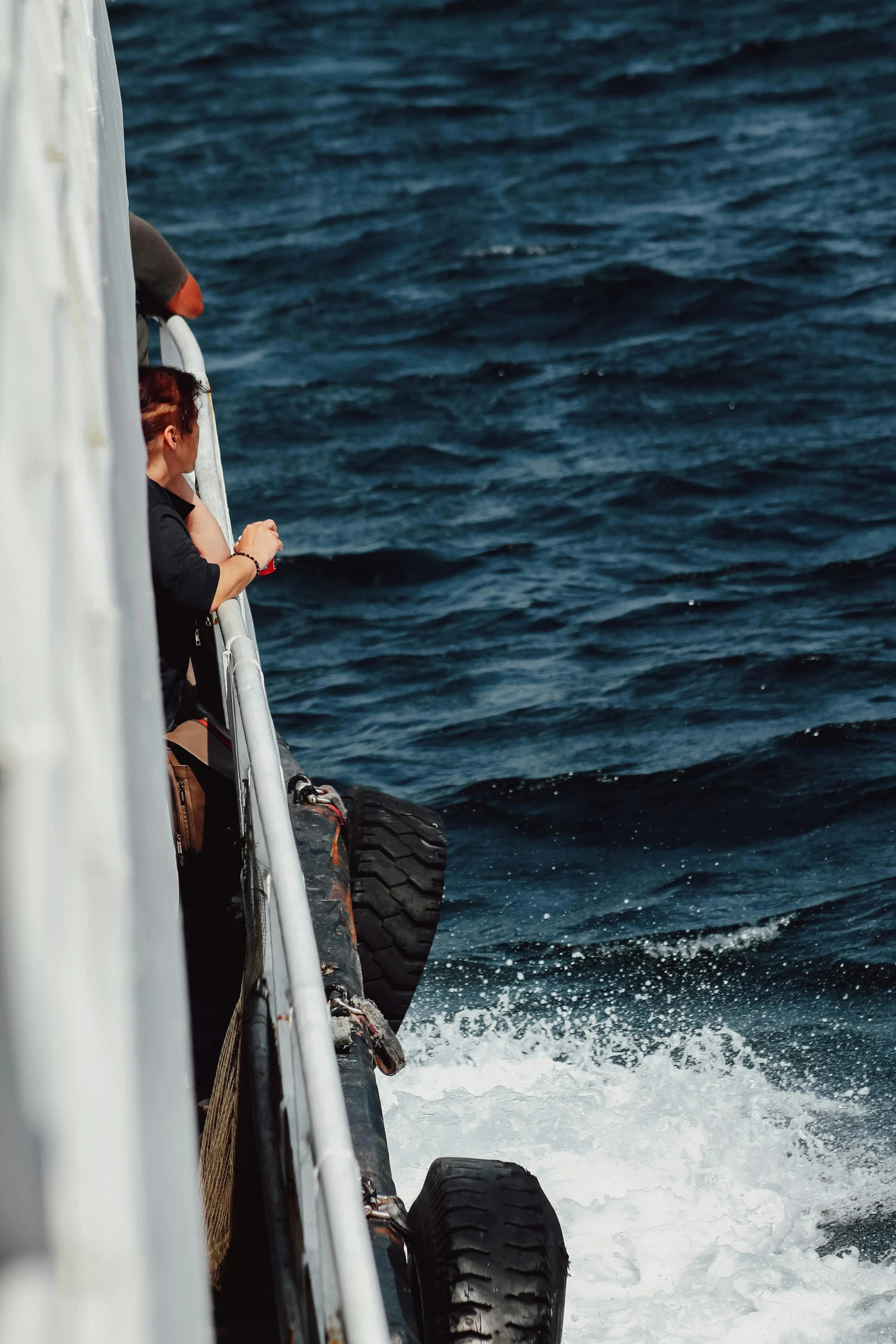 the young woman looks out on the water off of a ship