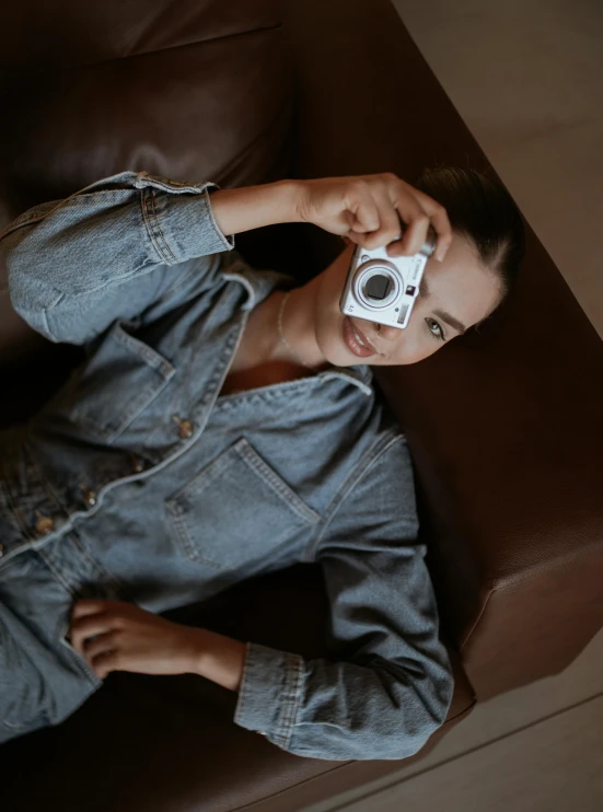 a man sits on a couch with his feet propped up and holding a camera up