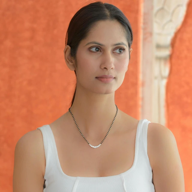 a young woman wearing a white top and a silver necklace