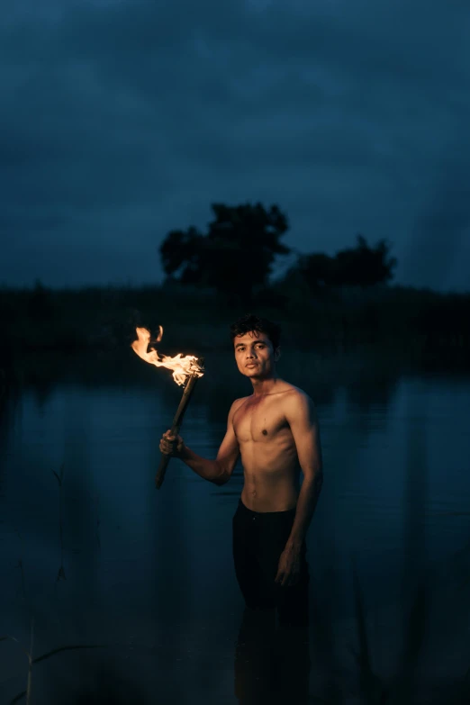 a man holding a flame stick at night