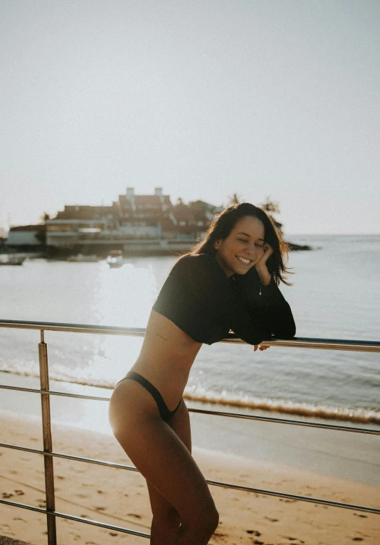 a  woman standing next to a metal rail on a beach