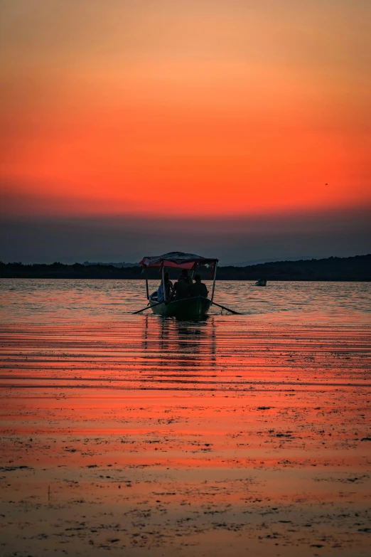 the sun rises over the water while the boat is traveling in the distance