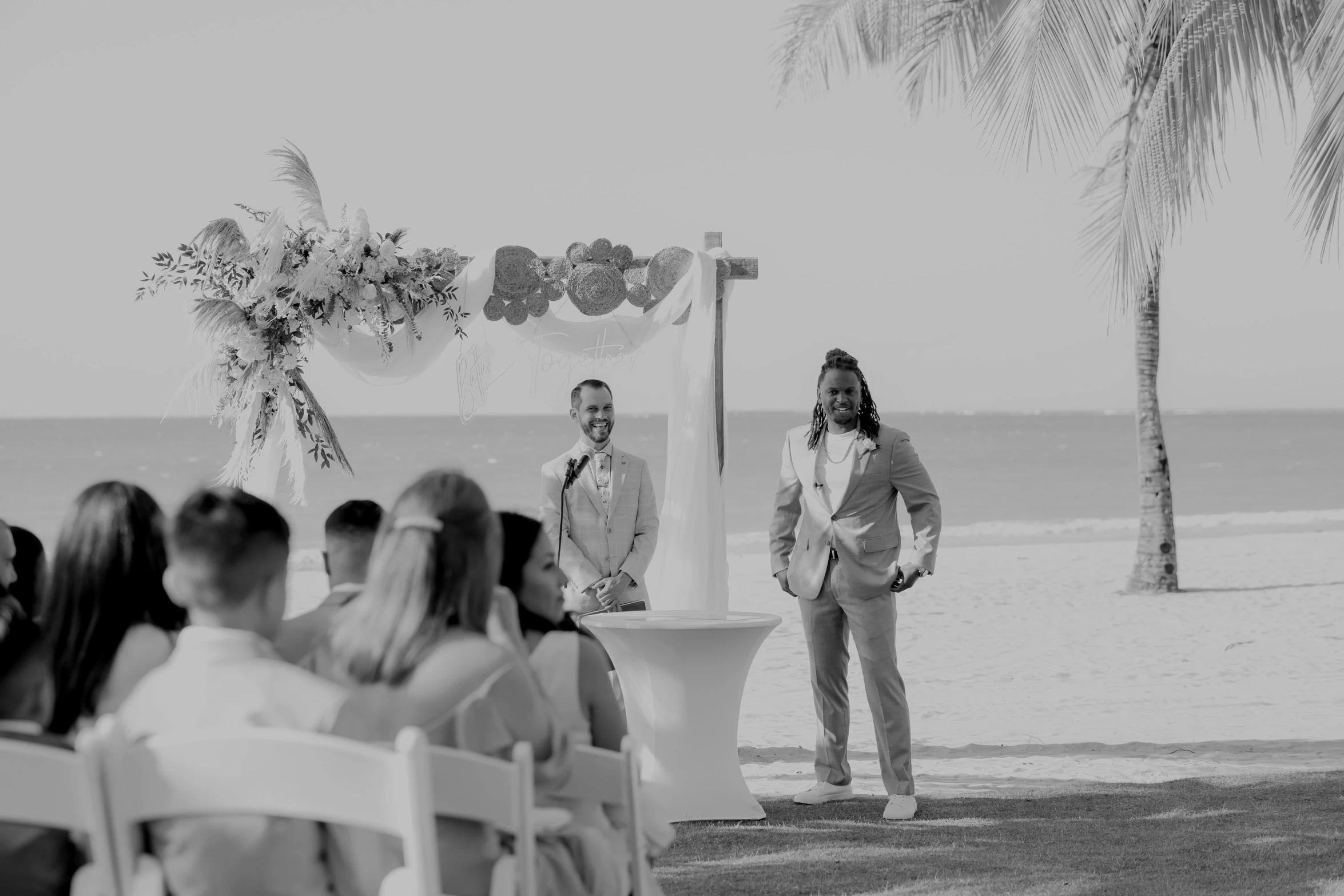 a groom and bride exchange vows on the beach as friends and family gather around the altar for their wedding ceremony