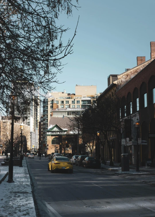 a small yellow car driving down a road next to tall buildings