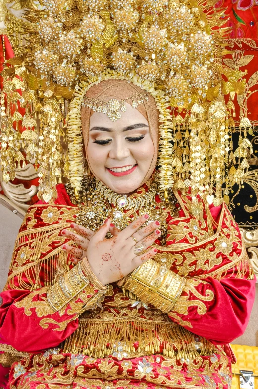 a woman dressed in a red and gold costume and holding her hands together