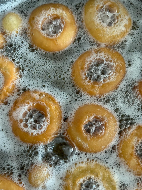 a bunch of doughnuts in oil with bubbles