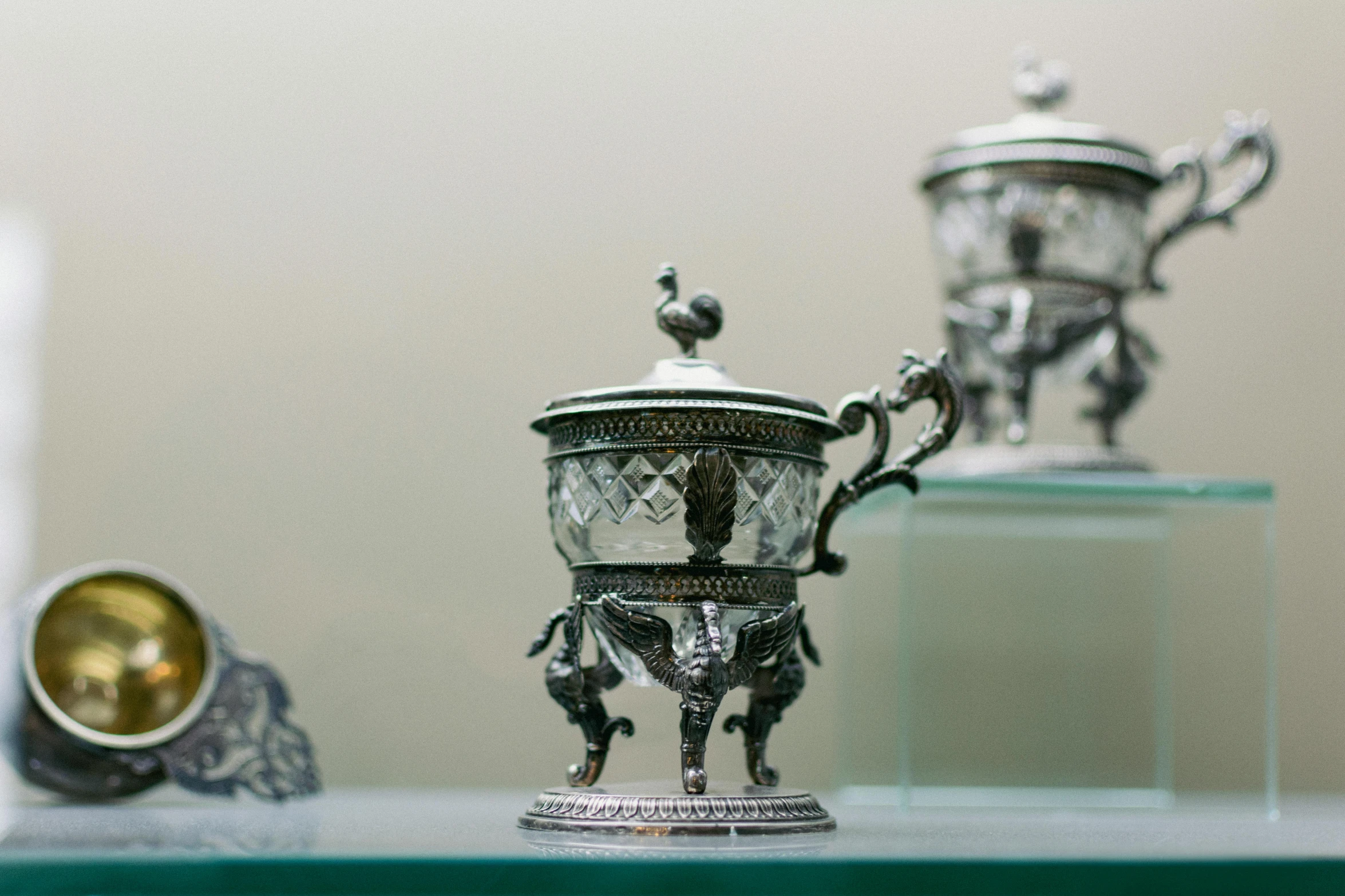 the antique silver cups and bowls sit on display