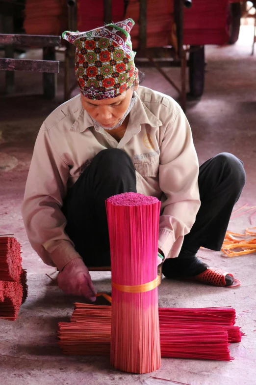 woman is weaving red yarn for decoration with a brush