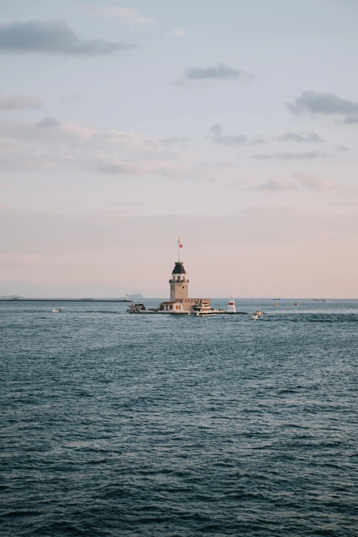 lighthouse in a body of water with boats in the background