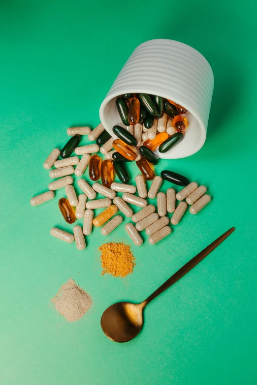 a can of orange pills, spoon and pills on a table