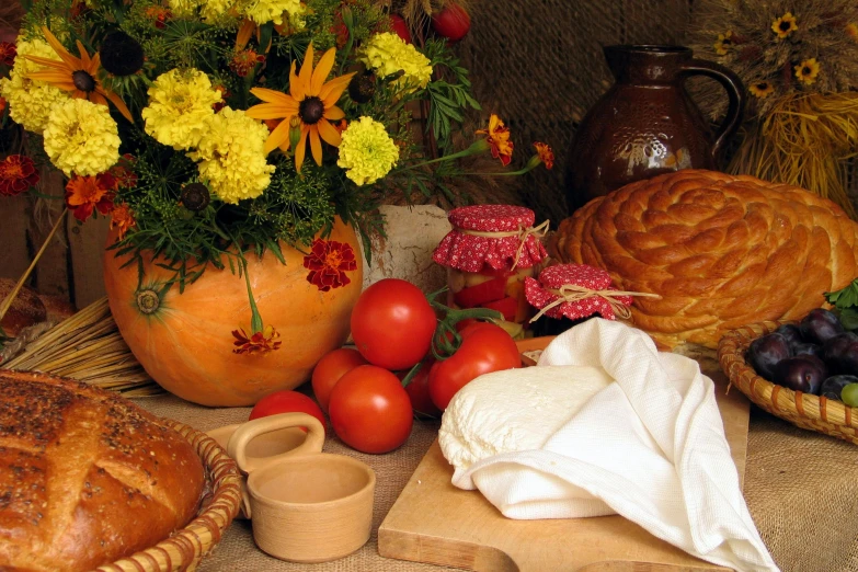 the flower arrangement is neatly arranged in front of various bread and fruit