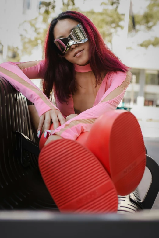 a woman with bright red hair and sun glasses sitting in a chair