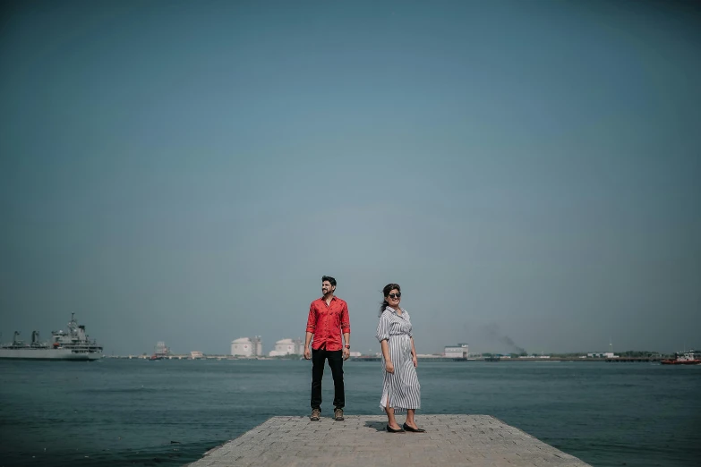 two people are on the pier at a river bank