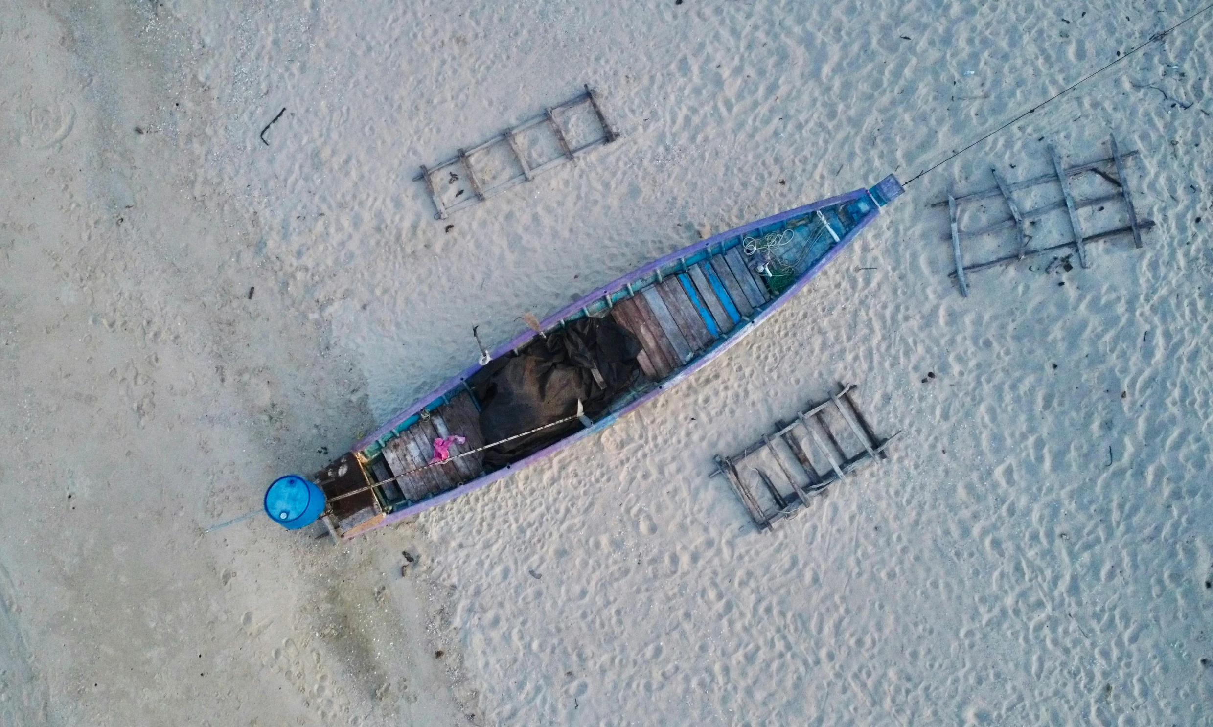 an overhead view of a blue canoe on the sand