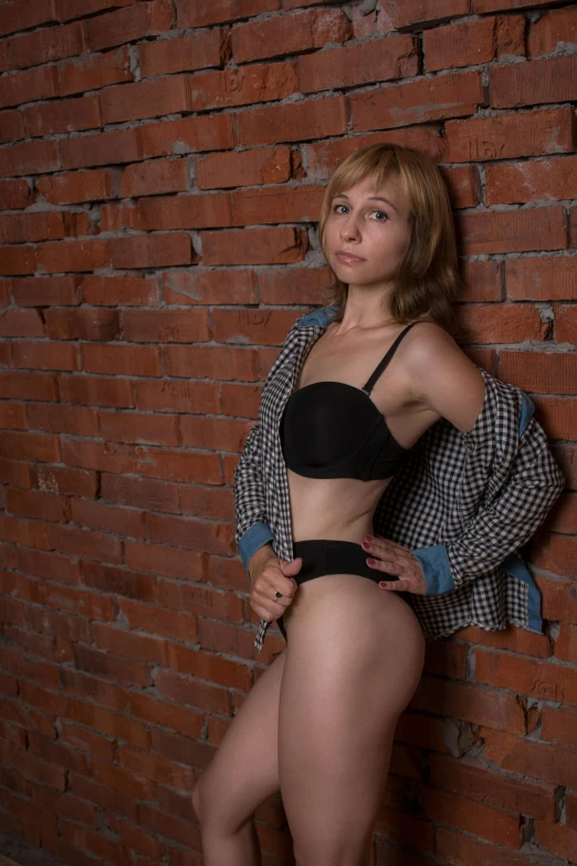 a woman in lingerie standing by a brick wall