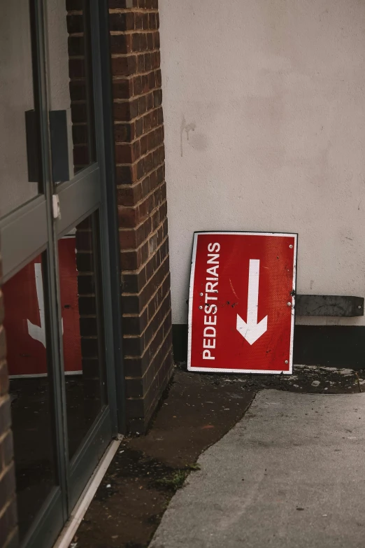 a red sign sitting on the sidewalk by a building