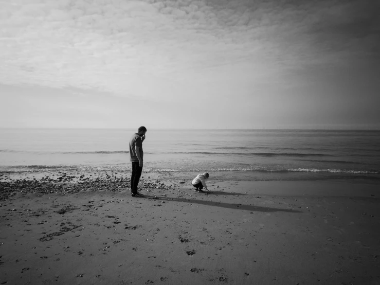 person and dog on beach, with water looking out toward horizon