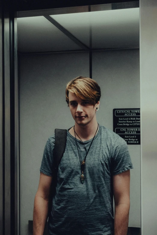 a young man is standing by a glass partition