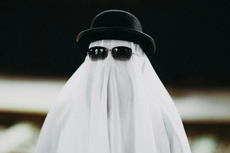 a ghost dressed in white and wearing dark glasses and a black hat