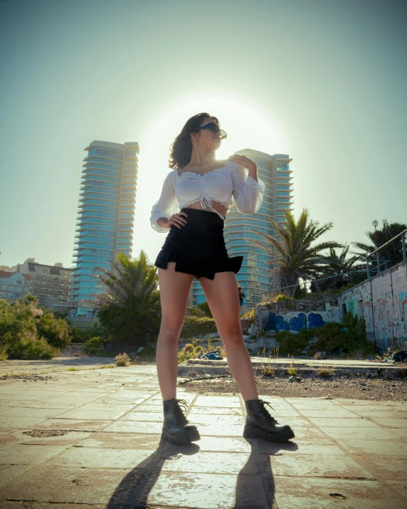 a woman with sunglasses is standing outside wearing a white shirt and black shorts