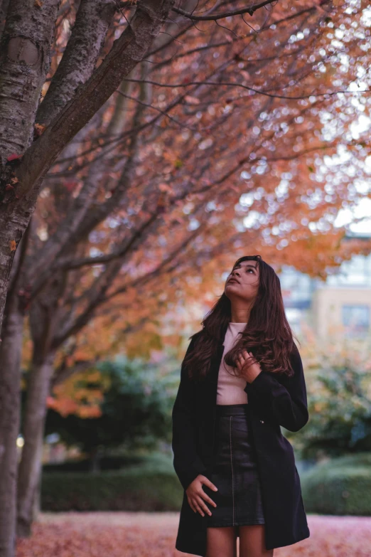 a woman standing in front of trees with its sun up