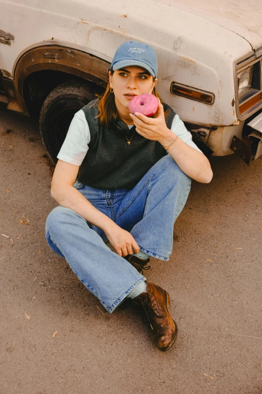 a woman in a cap eats a pink doughnut