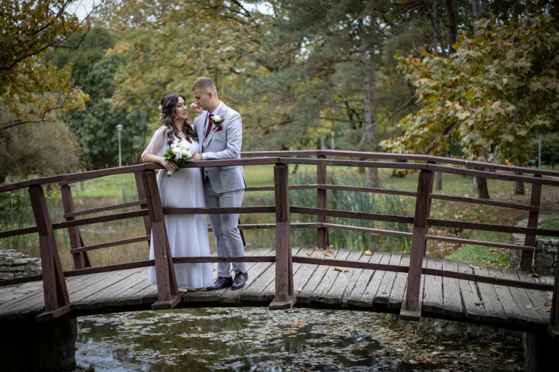 a couple stands together while posing on a bridge