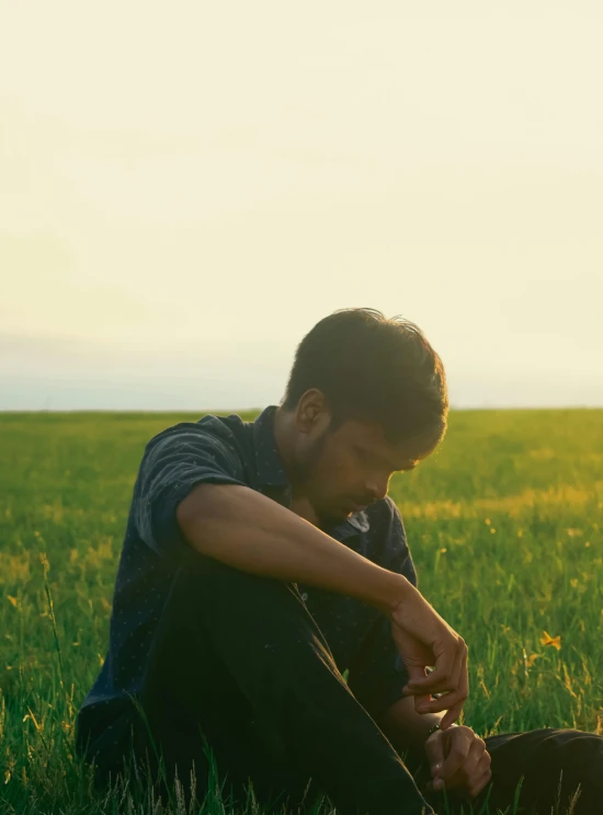 a man kneeling in a green field with his shoes on